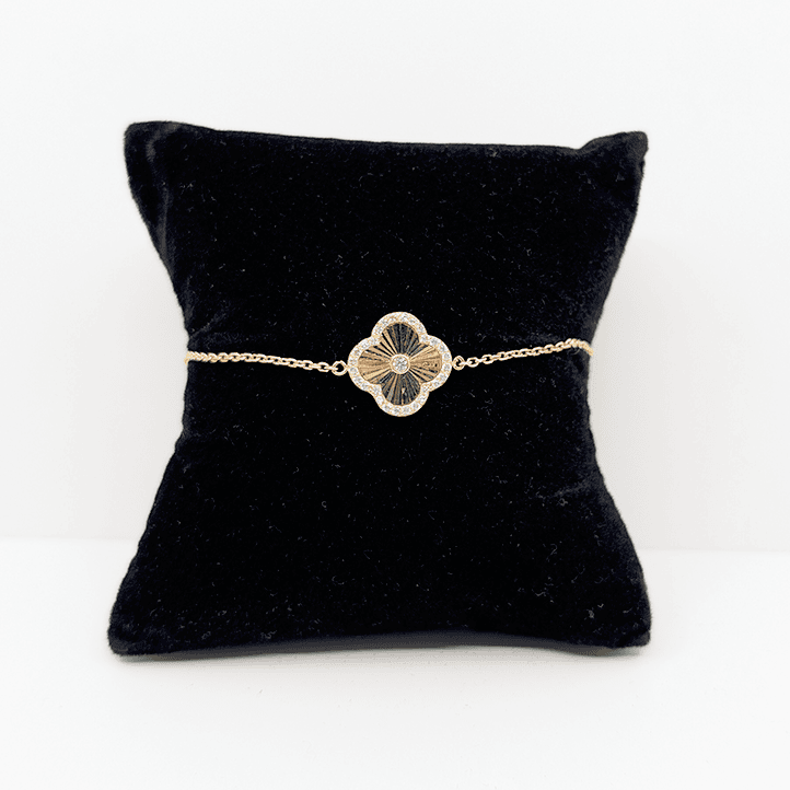 A 14k gold dainty chain bracelet with a single 14k gold clover charm with a cubic zirconia accent.