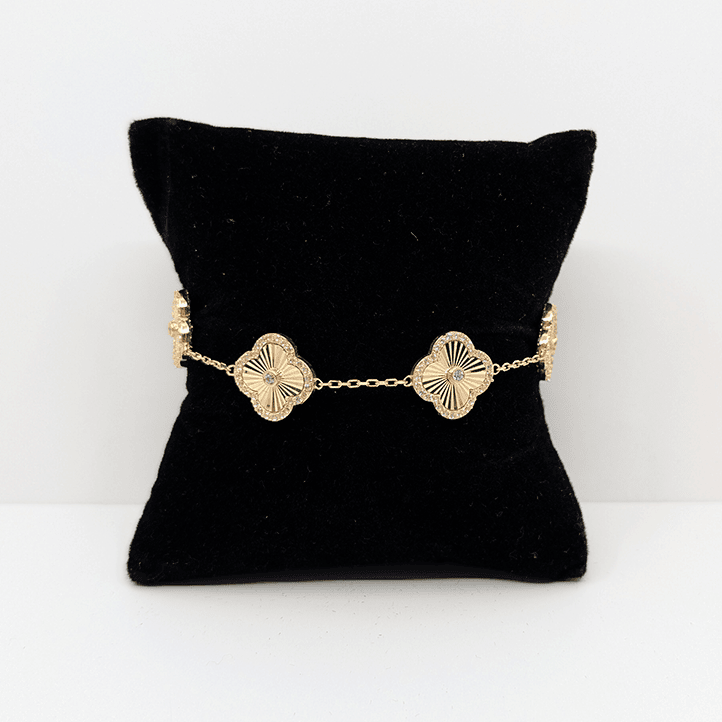 A 14k gold dainty chain bracelet with 14k gold clover charms with a cubic zirconia accent throughout.