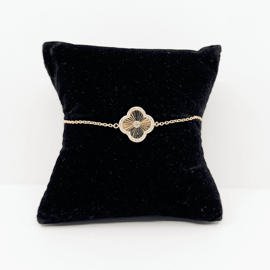 A 14k gold dainty chain bracelet with a single 14k gold clover charm with a cubic zirconia accent.