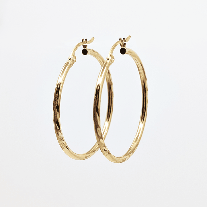 A 10k yellow gold medium hoop earring with diamond cut design. 