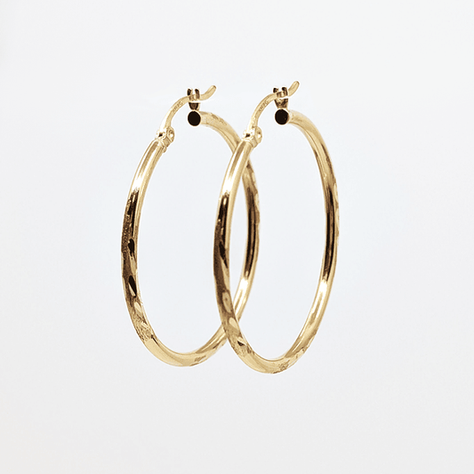 A 10k yellow gold medium hoop earring with diamond cut design. 